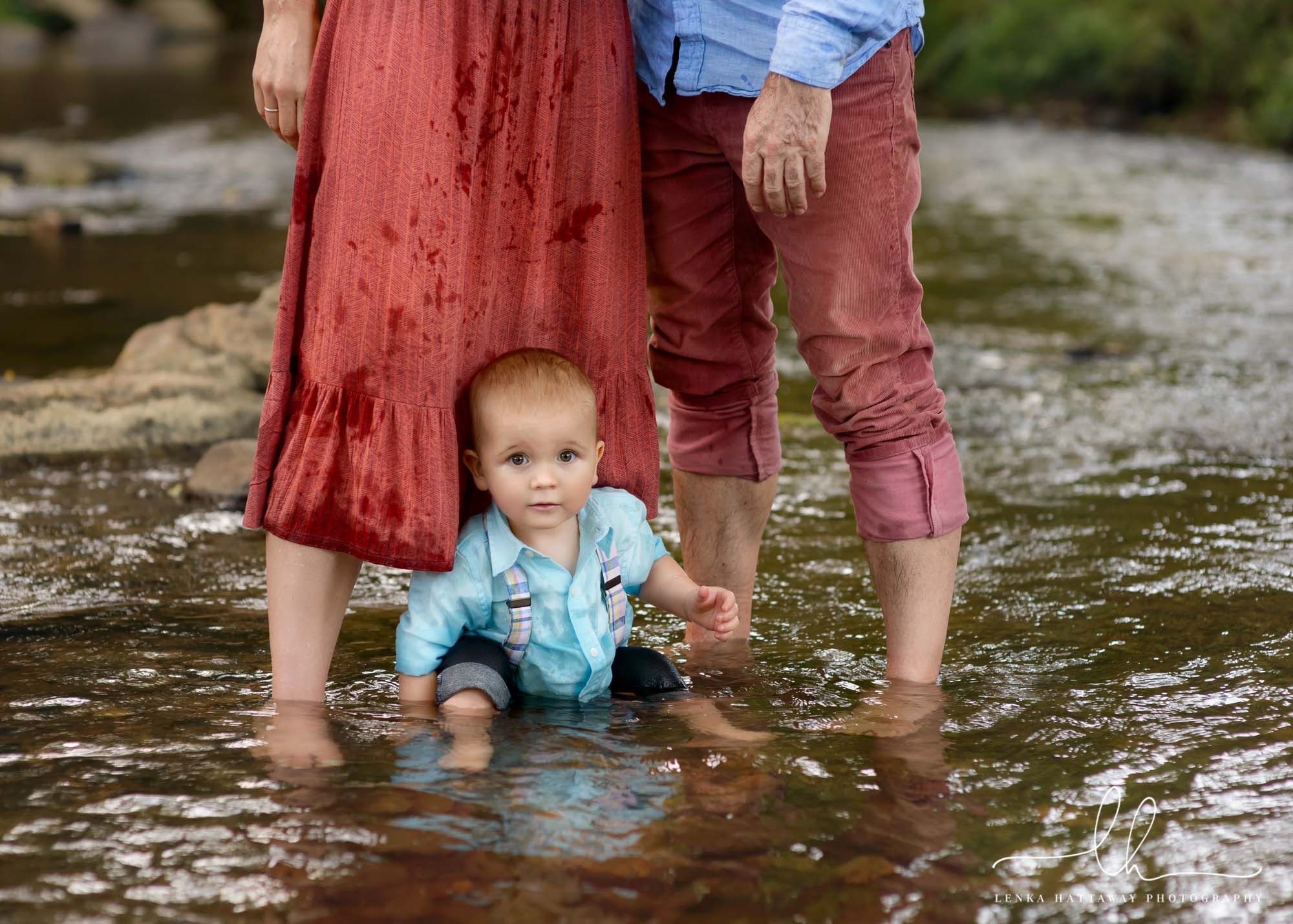 Family photography in the summer. Boy sitting in water.