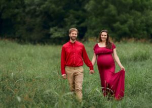 A couple walking, holding hands, during their maternity session.