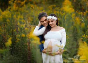 Maternity photo of a couple in a field of yellow flowers.
