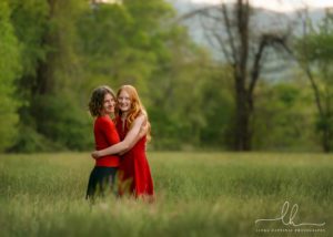 MOther and daughter hugging, standing in tall grass.