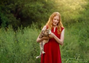 Photo of a girl in red dress holding a cat from a mother-daughter photo session in Asheville.