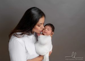 Portrait of a mom kissing her newborn baby.