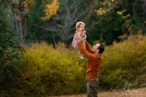 Dad playing with his daughter by holding her up in the air.