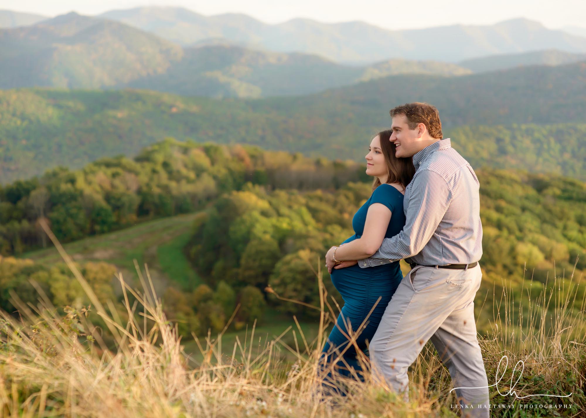 Maternity picture in the mountains. The couple is looking into the mountains.