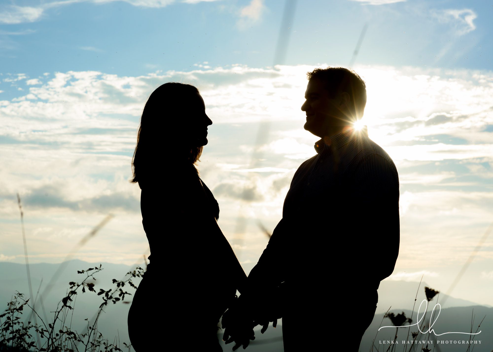 A silhouette of an expecting couple taken in the mountains.