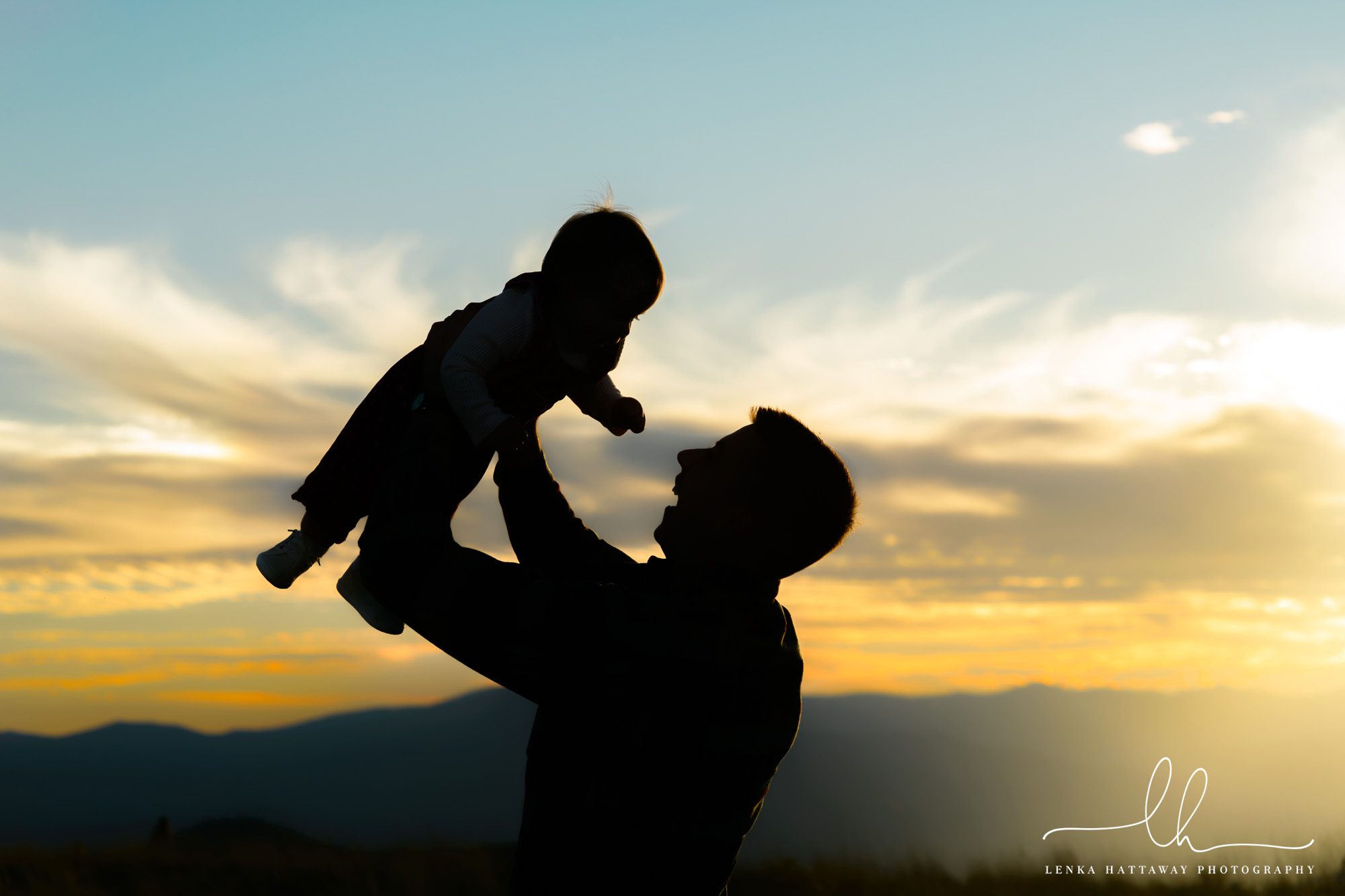 Lovely silhouette of dad and baby in the mountains.