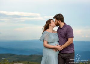 Sweet mountain pregnancy photo of a kissing couple.
