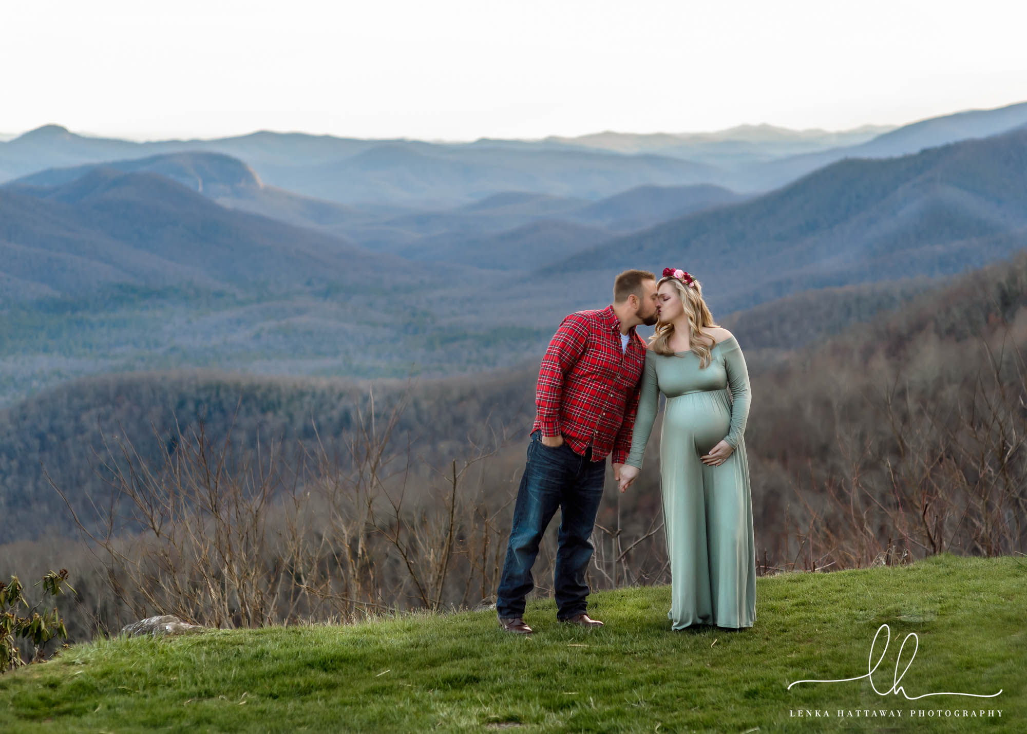 Couple kissing in a maternity photo in the mountains.